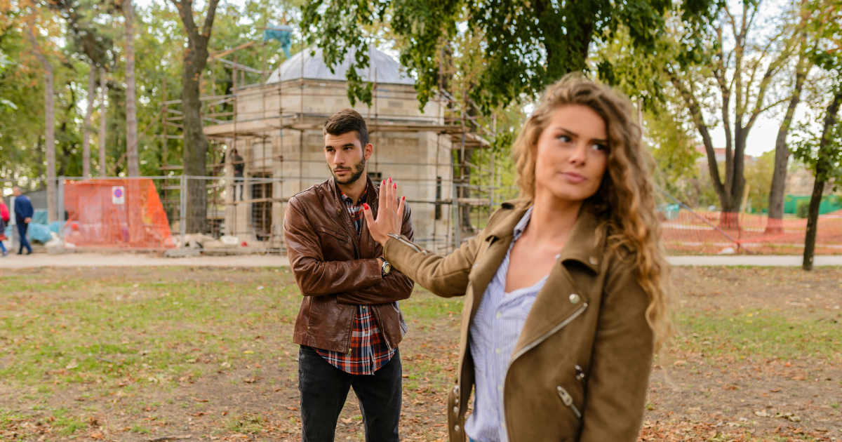 Woman rejecting man, concept for toxic stress in relationships and healing. Relationship problems in outdoor setting.