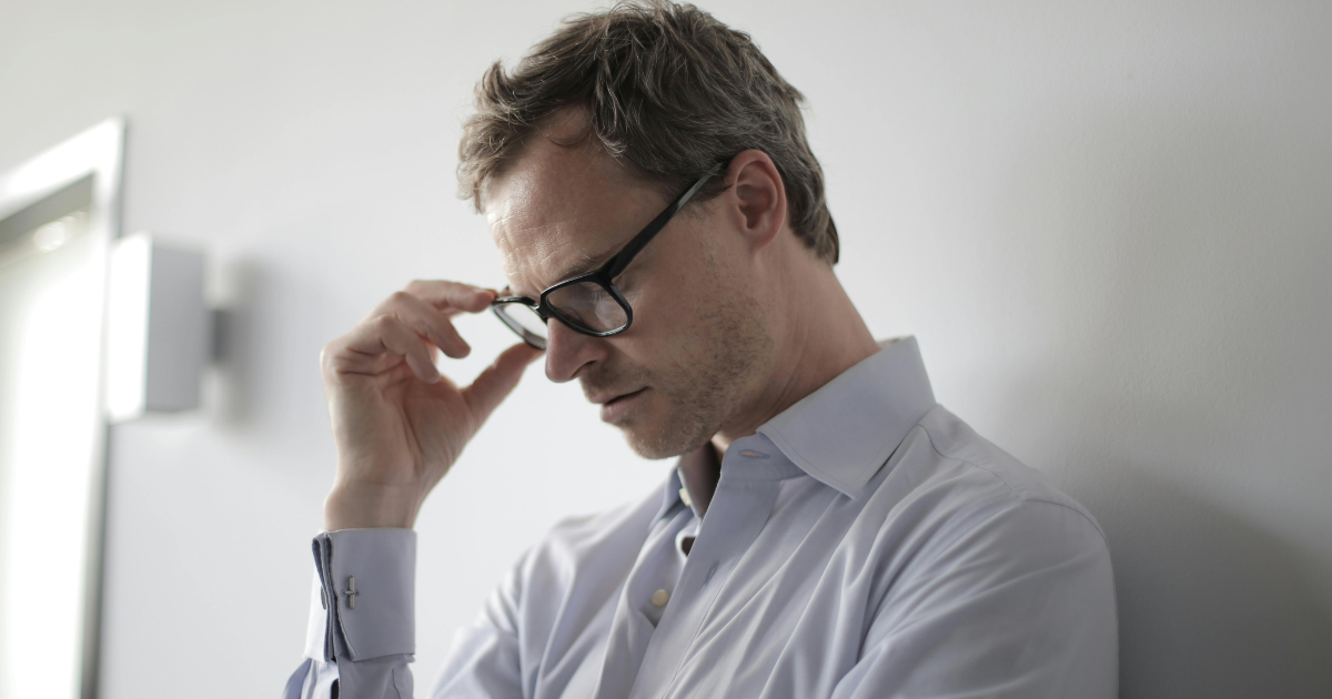 Stressed man in glasses. Concept: The Hidden Connection Between Stress and Mortality. Shows stress, anxiety, and mental health.
