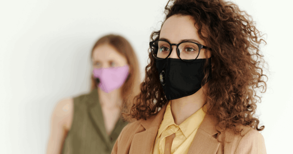 Woman wearing a face mask, addressing anxiety. Ketamine may help manage anxiety. Curly hair, glasses and professional attire.